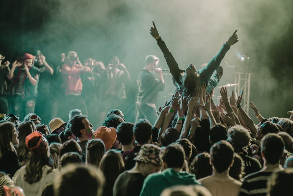 A vibrant concert scene with a crowd surfer and lively audience members enjoying a live performance.